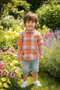 Boy 5-6 years in garden wearing orange plaid shirt